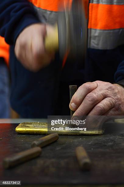 Bar of gold is manually stamped at Evolution Mining Ltd.'s gold operations in Mungari, Australia, on Wednesday, Aug. 5, 2015. A declining gold price,...