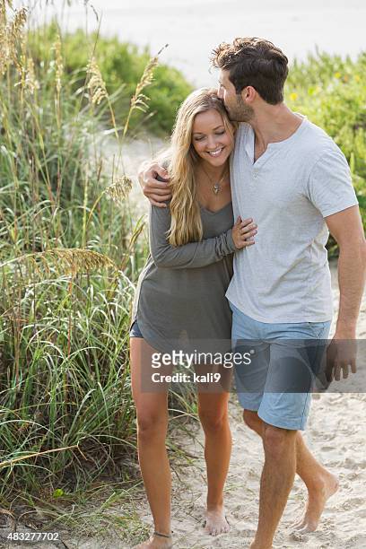 young romantic couple walking on beach sand dunes - couple dunes stockfoto's en -beelden