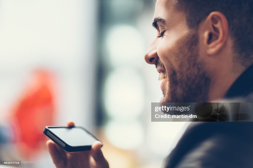 Smiling man using smartphone to watch tv