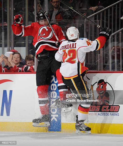 Mark Cundari of the Calgary Flames hits Steve Bernier of the New Jersey Devils into the boards during the second period at the Prudential Center on...