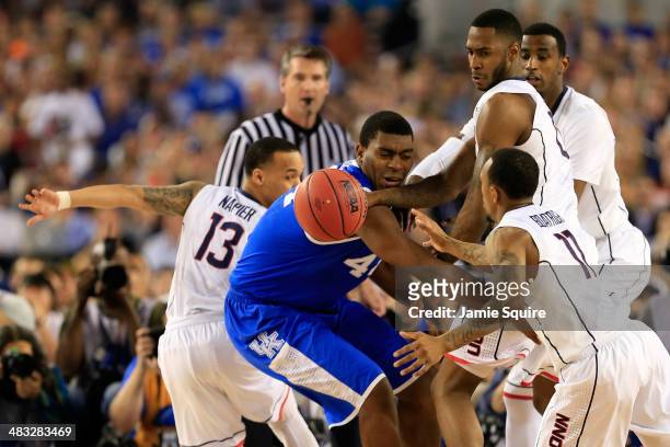 Dakari Johnson of the Kentucky Wildcats battles for a loose ball against Phillip Nolan and Ryan Boatright of the Connecticut Huskies during the NCAA...