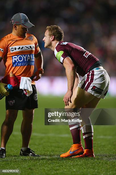 Daly Cherry-Evans of the Eagles grimaces as he holds his knee while receiving attention from the trainer during the round 22 NRL match between the...