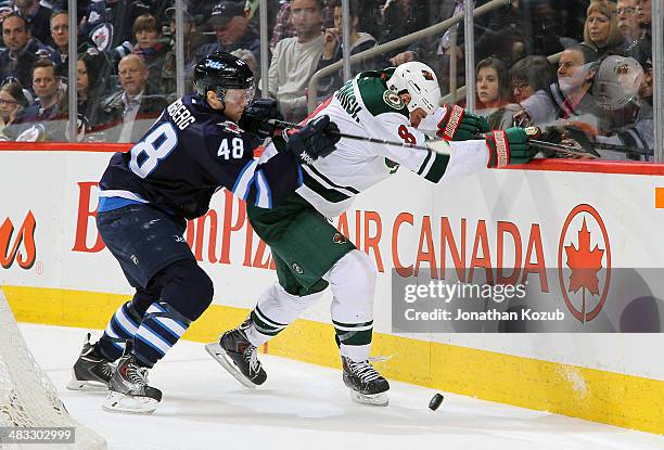 Cody McCormick of the Minnesota Wild protects the puck from Carl Klingberg of the Winnipeg Jets along the boards during third-period action at the...