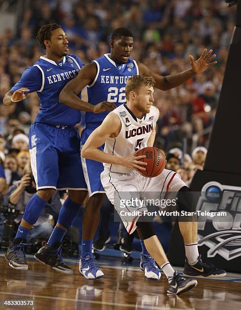 Connecticut Huskies guard/forward Niels Giffey looks to pass, defended by Kentucky Wildcats guard/forward James Young and Alex Poythress as the...
