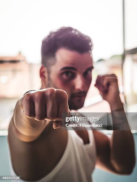 joven hombre tirando de un punzón - puño manga fotografías e imágenes de stock