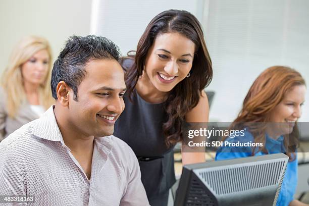 teacher assisting man with computer during corporate training class - indian college stockfoto's en -beelden