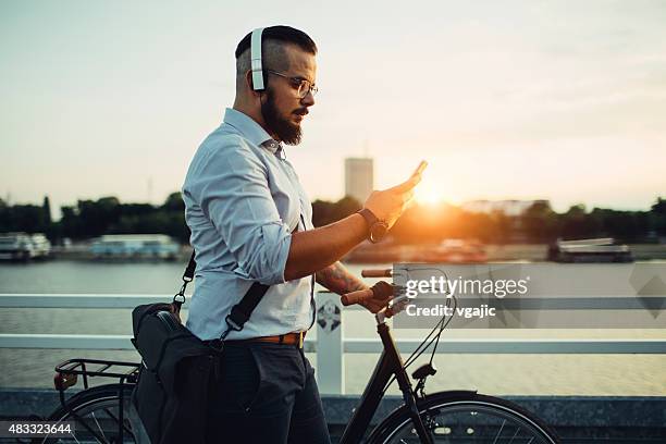 businessman push bicycle and using smartphone outdoors. - music city walk stock pictures, royalty-free photos & images