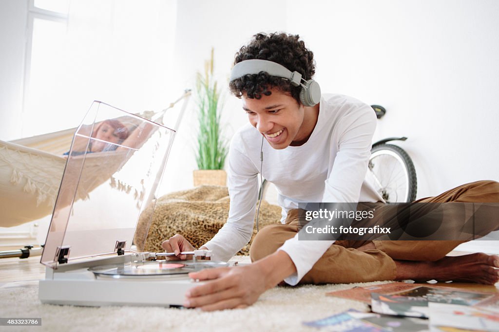 Young african man with big earphones and record player