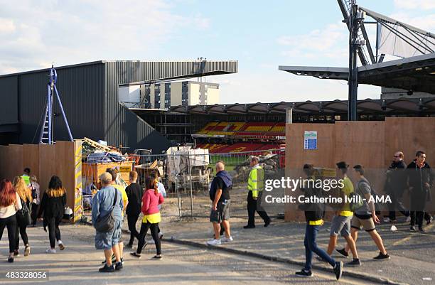 Fans walk past the fence as building work continues before the pre-season friendly between Watford and Seville at Vicarage Road on July 31, 2015 in...