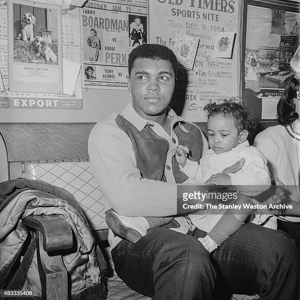 Cassius Clay sits with his daughter after training for his title defense against Sonny Liston on February 22, 1965 in Chicago, Illinois.