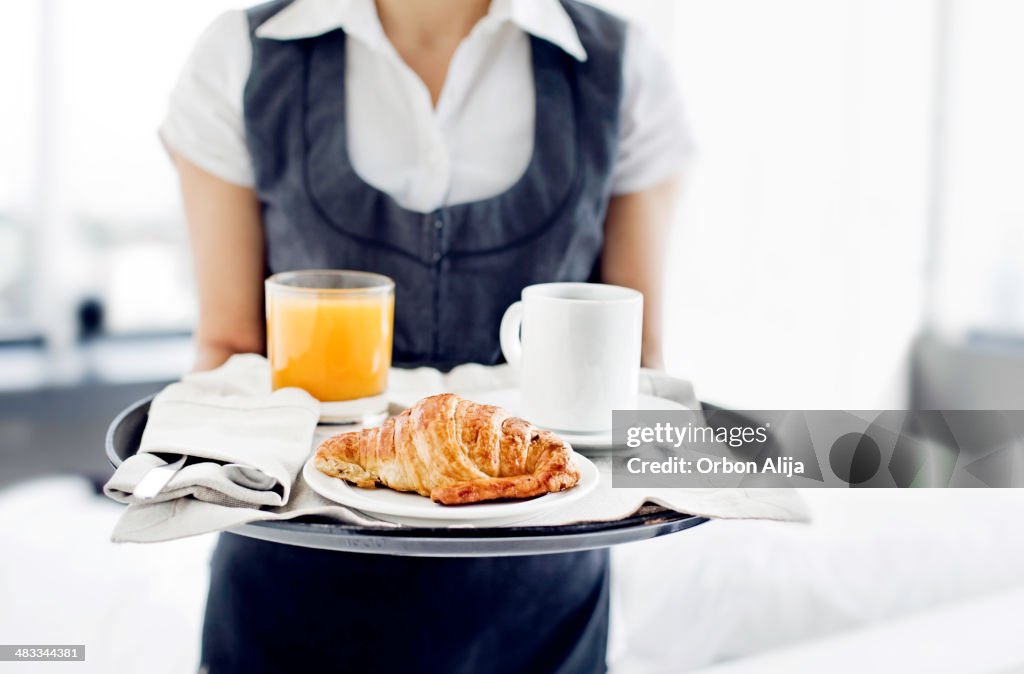 Room service hotel staff carries breakfast tray