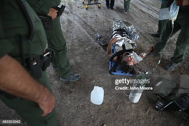 Border Patrol agents wait for paramedics to take an undocumented immigrant to the hospital after he collapsed from heat exhaustion after crossing...