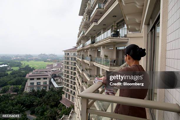 An employee cleans the railing of a balcony at Mission Hills Resort Haikou in Haikou, Hainan Province, China, on Saturday, April 5, 2014. The yuan is...