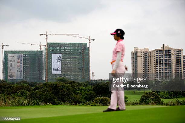 Buildings stand under construction on the site of the Mission Hills Lan Kwai Fong development, as a golfer looks out from the green at Mission Hills...