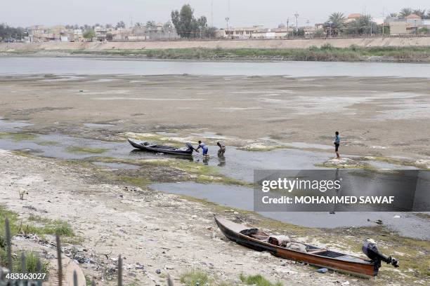 Iraqi men move a boat that was stuck on the banks of the Euphrates river in Twairij, roughly 20 kilometres east of Karbala, due to a decline in the...