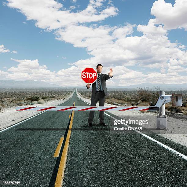 businessman stopping traffic at roadblock - barricade stock pictures, royalty-free photos & images