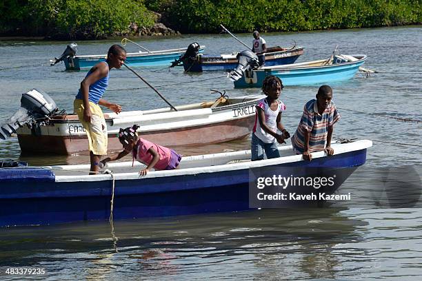 Children of a small fishing village seen on a speed boat at bay trying to catch small fish with their hooks and threads on January 25, 2014 in...