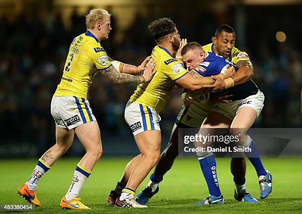 Brad Singleton of Leeds Rhinos is tackled by Roy Asotasi and Joe Philbin of Warrington Wolves during the Round 1 match of the First Utility Super...