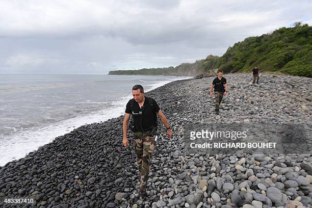 Police officers from Saint-Benoit's gendarmerie look for debris from the ill-fated Malaysia Airlines flight MH370 on a beach in Sainte-Marie de la...