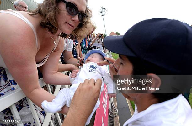 Alastair Cook of England signs an England outfit worn by a baby for a fan after day three of the 4th Investec Ashes Test match between England and...