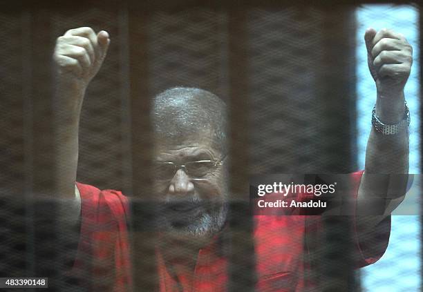 Former Egyptian President Mohamed Morsi gestures as he stands inside the defendants' cage in a courtroom at the police academy during his trial over...