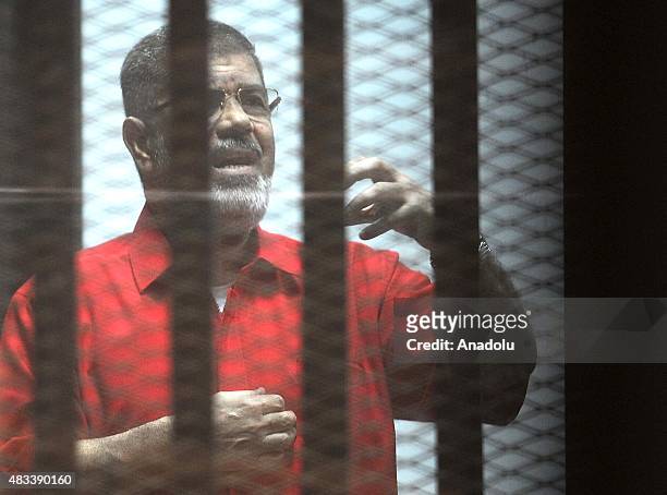 Former Egyptian President Mohamed Morsi gestures as he stands inside the defendants' cage in a courtroom at the police academy during his trial over...