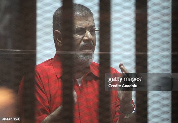 Former Egyptian President Mohamed Morsi gestures as he stands inside the defendants' cage in a courtroom at the police academy during his trial over...