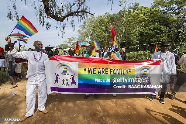 People hold a banner reading "We are Family" while waving rainbow flags as they take part in the Gay Pride parade in Entebbe on August 8, 2015....
