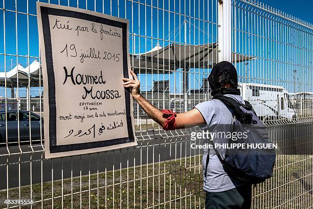 Protester holds a sign reading "17-year-old Eritrean Houmed Moussa died on July 19, 2015 while trying to cross the Eurotunnel" as he stands behind a...