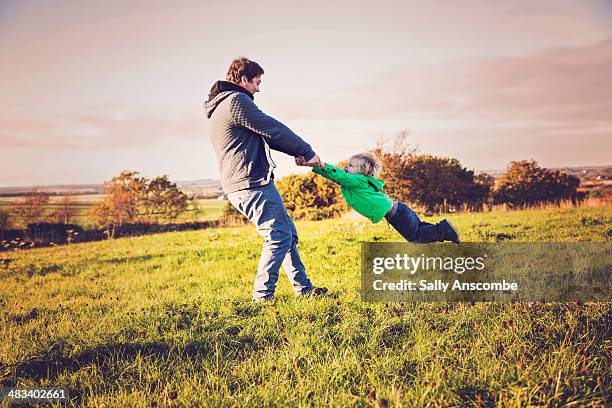 father and son playing outdoors - turning stock pictures, royalty-free photos & images