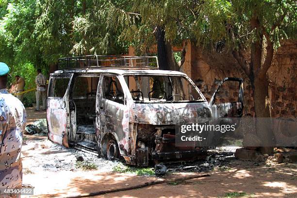 Photo taken on August 8, 2015 shows a burned vehicle in front of the Hotel Byblos in the central Malian town of Sevare, after gunmen stormed the...