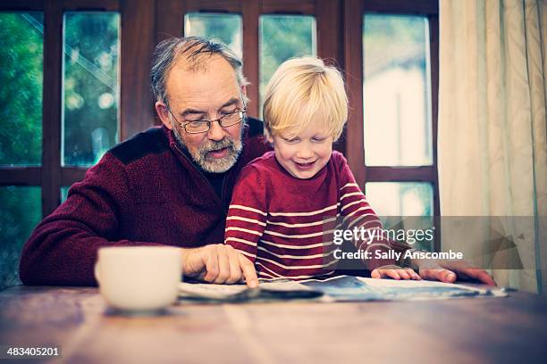 grandfather and grandchild reading the paper - elementary student stock pictures, royalty-free photos & images