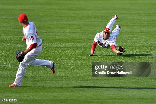 Cesar Hernandez watches as Ben Revere of the Philadelphia Phillies dives unsuccessfully for the ball hit by Scooter Gennett of the Milwaukee Brewers...