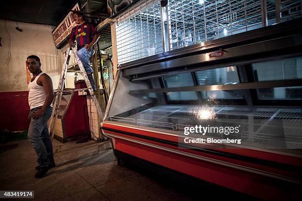 Workers stand while making repairs to a looted store in San Felix, Venezuela, on Thursday, Aug. 6, 2015. Venezuela, where about 70 percent of...