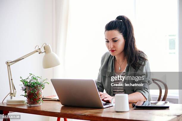 young brunette blick auf laptop - brunette sitting at desk stock-fotos und bilder