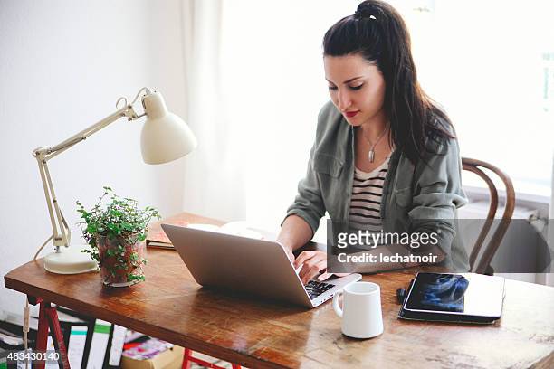 young brunette blick auf laptop - brunette sitting at desk stock-fotos und bilder