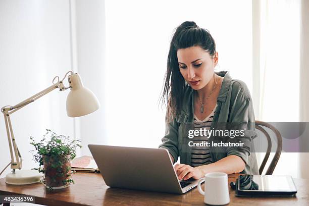 young brunette blick auf laptop - brunette sitting at desk stock-fotos und bilder