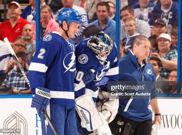 Goalie Ben Bishop of the Tampa Bay Lightning is helped off the ice by teammate Eric Brewer and head athletic trainer Tom Mulligan after sustaining an...