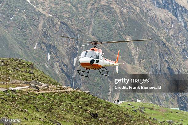 Helicopter is flying close to the surface through the mountains, providing a shuttle service for Pilgrims visiting Kedarnath Temple.