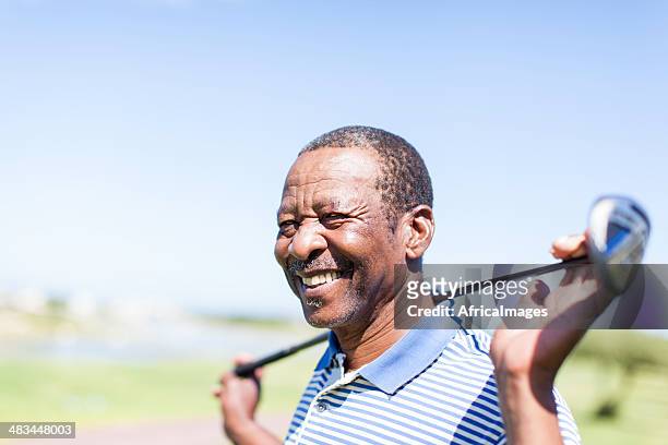 african senior golfer holding his club with a smile. - golf stock pictures, royalty-free photos & images