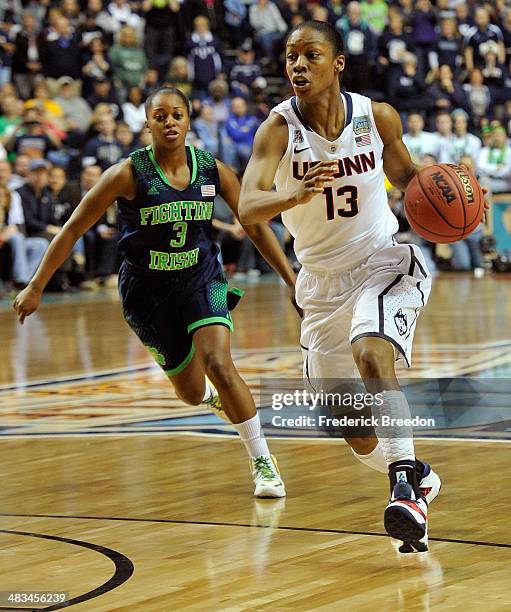 Brianna Banks of the Connecticut Huskies dribbles past Whitney Holloway of the Notre Dame Fighting Irish during the NCAA Women's Basketball...