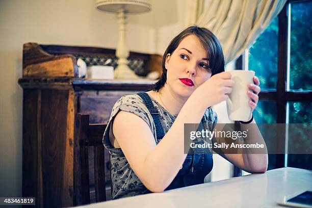 young woman relaxing at home with a mug of tea - coveralls stock pictures, royalty-free photos & images