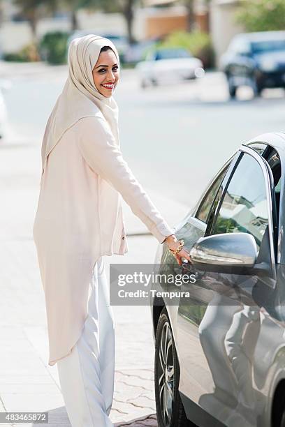 middle easter woman entering a luxury car in dubai - dubai woman driving car stockfoto's en -beelden