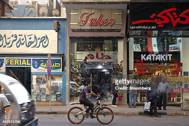 Man rides a bicycle past stores on a street in Cairo, Egypt, on Friday, Aug. 7, 2015. The Suez canal extension and other construction projects have...