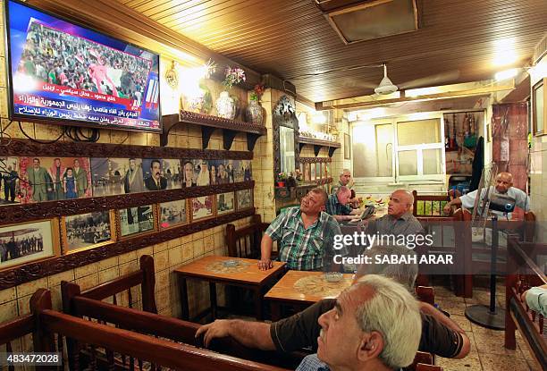 Iraqis watch the news on TV at a cafe on August 9, 2015 on al-Rasheed street in the capital Baghdad as Iraqi Prime Minister Haider al-Abadi called...