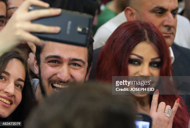 Lebanese pop star Haifa Wehbe poses for pictures with her fans as she arrives for the Premiere of he movie 'Halawet Rooh' at a movie theatre in the...