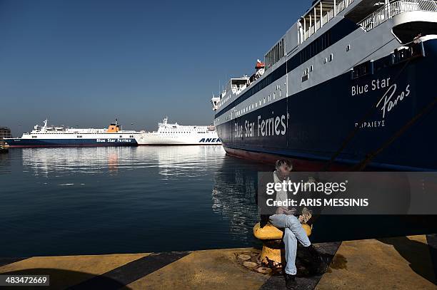 Man sits in front of docked ferries at the port of Piraeus during a 24-hour general strike in Athens on April 9, 2014. The boards of the General...