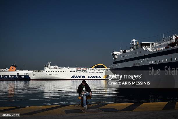 Man sits in front of docked ferries at the port of Piraeus during a 24-hour general strike in Athens on April 9, 2014. The boards of the General...