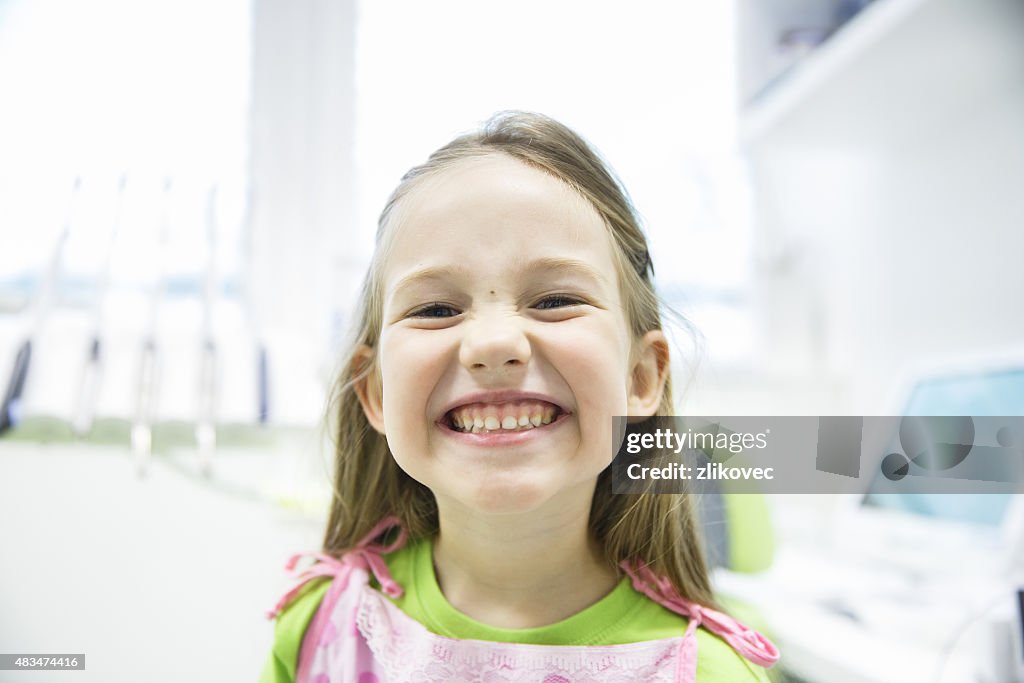 Girl showing her healthy milk teeth at dental office