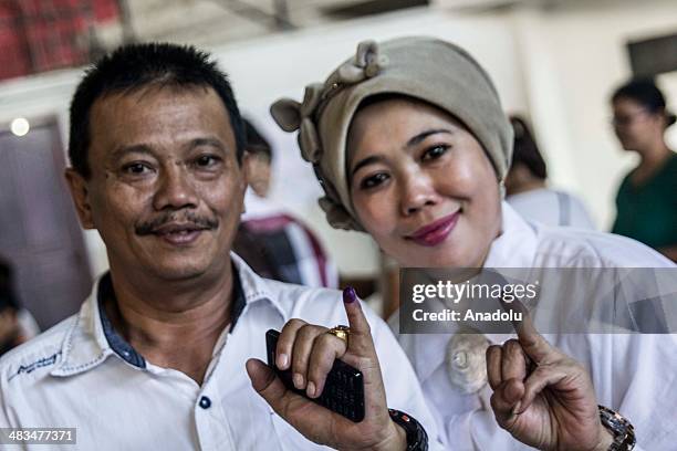 An Indonesian couple shows their ink-stained fingers after casting their ballots for Indonesia's legislative elections at a polling station on April...